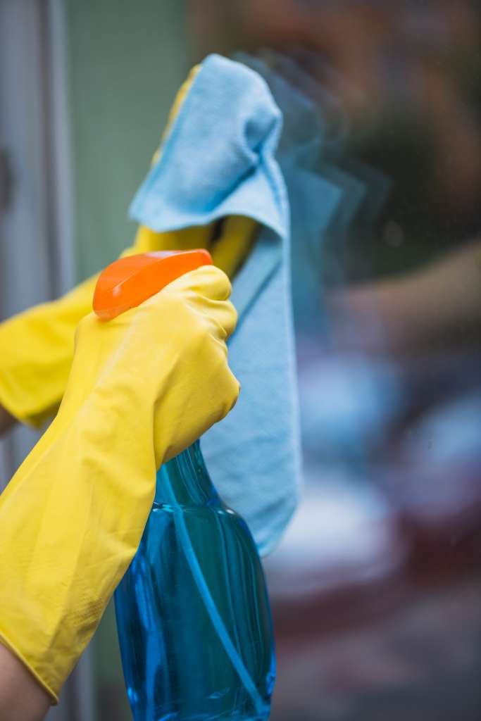 ama-de-casa-fumigacion-detergente-con-botella-de-spray-en-la-ventana-de-vidrio